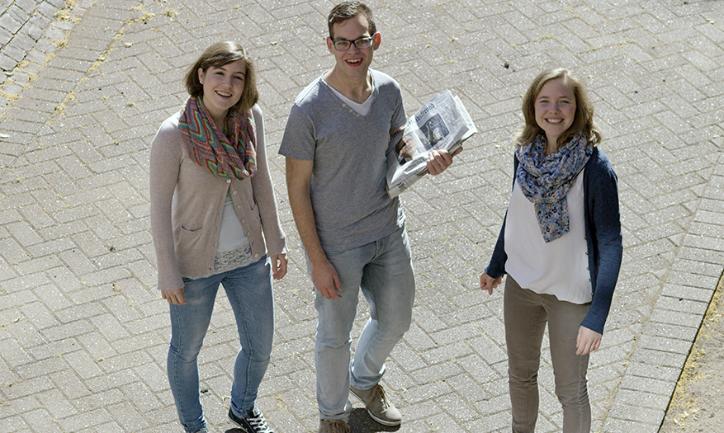 Zwei Frauen und ein Mann stehen zusammen und lachen