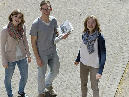 Zwei Frauen und ein Mann stehen zusammen und lachen