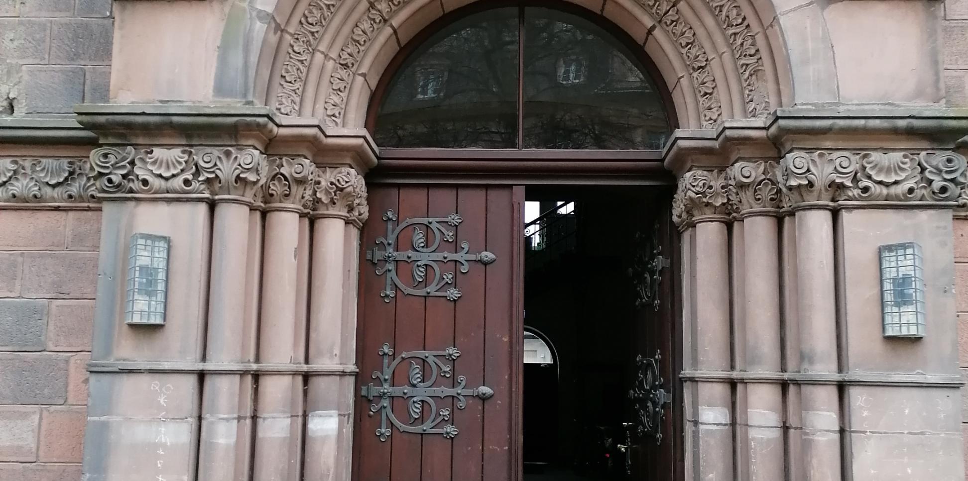 ein Sandsteinportal mit geöffneter Tür. Darüber das PX